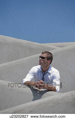 Stock Photo - Man with tie and sunglasses standing behind wall. Fotosearch