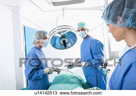Stock Image - Medical personnel in operating room. Fotosearch