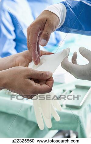 Medical personnel's hands putting on gloves in operating room View Large Photo Image Stock Image - Medical personnel's hands putting on gloves in operating room. Fotosearch