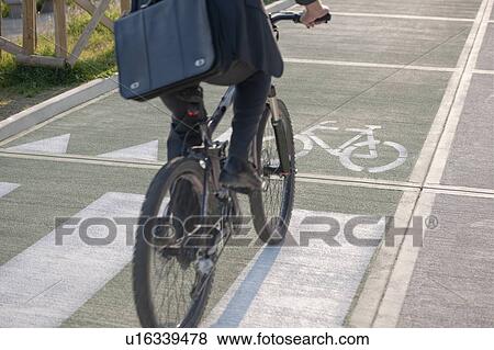 Stock Photo - Partial view of man riding bicycle in bicycle lane. Fotosearch