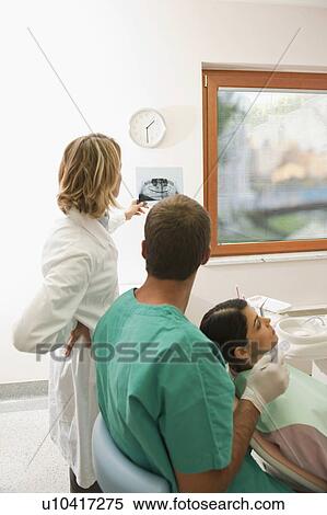 Stock Photography - Patient with dental professionals looking at dental panoramic xray. Fotosearch