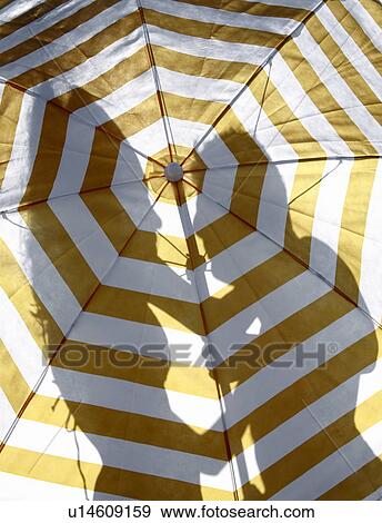 Silhouette of couple on the beach behind umbrella View Large Photo Image Stock Photo - Silhouette of couple on the beach behind umbrella. Fotosearch
