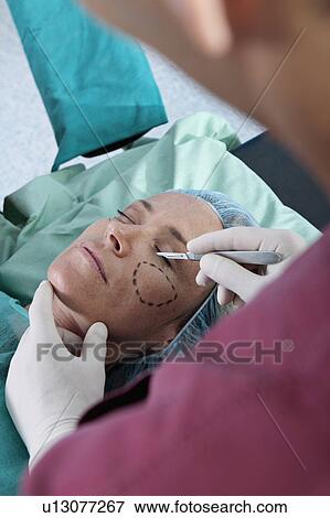Surgeon holding scalpel to patient's face View Large Photo Image Stock Photo - Surgeon holding scalpel to patient's face. Fotosearch