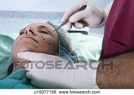 Surgeon with scalpel to patient's face View Large Photo Image Stock Photograph - Surgeon with scalpel to patient's face. Fotosearch