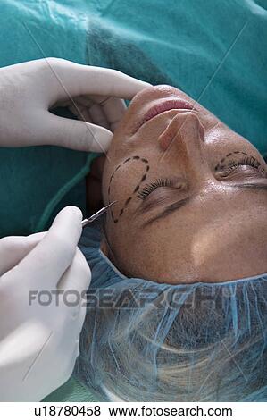 Stock Photo - Surgeon's hand with scalpel to patient's face. Fotosearch
