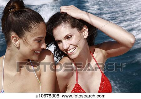 Stock Photo - Two female young adults on speedboat. Fotosearch