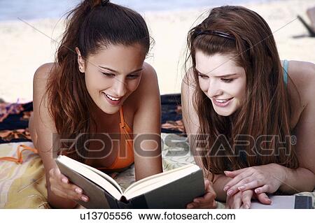 Two female young adults reading books on beach View Large Photo Image Stock Photograph - Two female young adults reading books on beach. Fotosearch