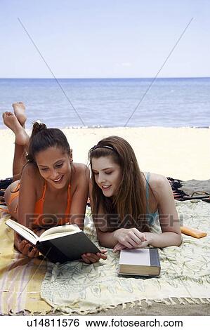 Two female young adults reading books on beach View Large Photo Image Stock Photograph - Two female young adults reading books on beach. Fotosearch