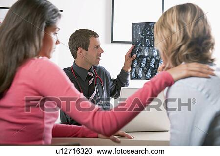 Stock Image - Woman consoling patient at doctor's visit. Fotosearch