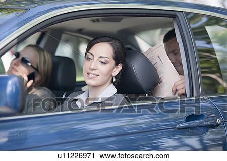 Stock Image - Woman driving car with two other people. Fotosearch