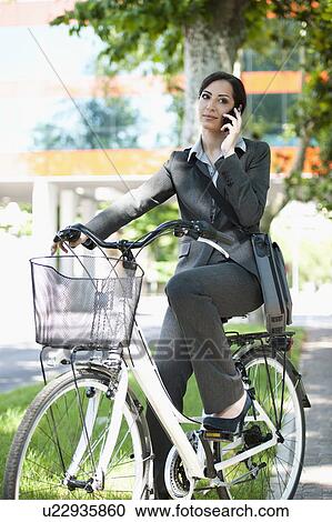 Woman in suit on bicycle talking on cellphone View Large Photo Image Stock Image - Woman in suit on bicycle talking on cellphone. Fotosearch