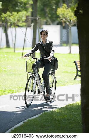Stock Image - Woman in suit riding bike. Fotosearch