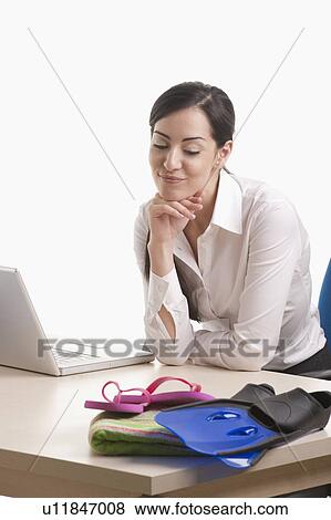Woman sitting at desk looking at beach gear View Large Photo Image Stock Photo - Woman sitting at desk looking at beach gear. Fotosearch