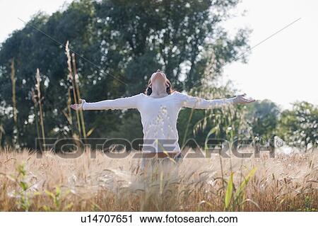 Stock Image - Woman with arms stretched out in wheat field. Fotosearch