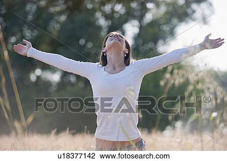 Stock Image - Woman with arms stretched out in wheat field. Fotosearch