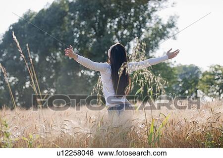 Woman with arms stretched out in wheat field View Large Photo Image Stock Photo - Woman with arms stretched out in wheat field. Fotosearch