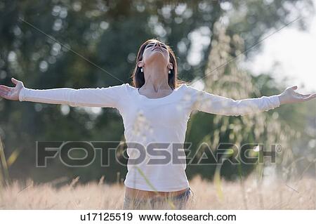 Woman with arms stretched out in wheat field View Large Photo Image Stock Photo - Woman with arms stretched out in wheat field. Fotosearch