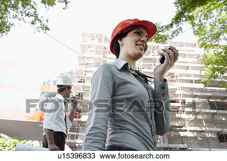 Woman with hardhat and man on walky talky at construction site View Large Photo Image Stock Image - Woman with hardhat and man on walky talky at construction site. Fotosearch