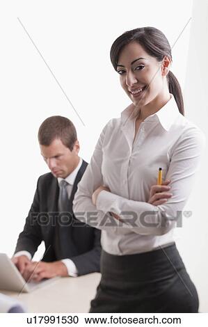 Stock Image - Woman with man in background at laptop. Fotosearch
