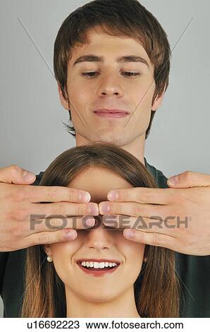 Young adult male holding hands over woman's eyes View Large Photo Image Stock Image - Young adult male holding hands over woman's eyes. Fotosearch