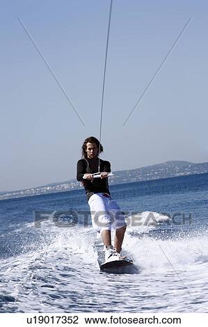 Stock Image - Young adult male waterskiing. Fotosearch