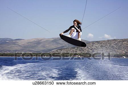 Stock Image - Young adult male waterskiing. Fotosearch