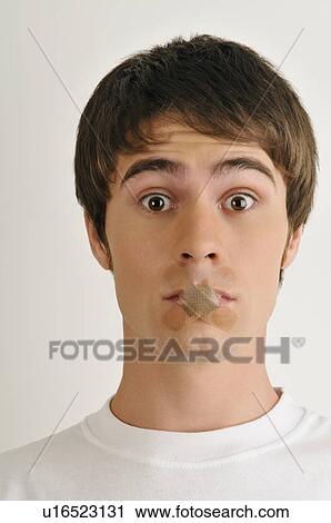 Stock Image - Young male adult; Band-Aids over mouth. Fotosearch