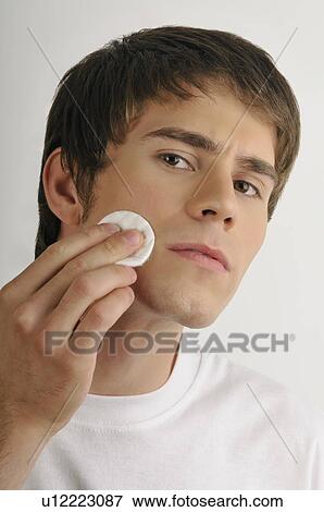 Young male adult cleaning face with cotton pad View Large Photo Image Stock Photo - Young male adult cleaning face with cotton pad. Fotosearch