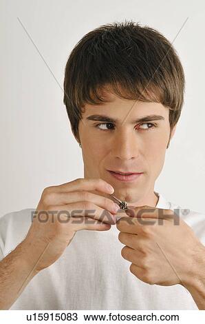 Stock Image - Young male adult cutting finger nails. Fotosearch