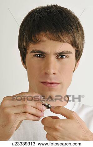 Stock Image - Young male adult cutting finger nails. Fotosearch