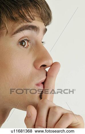 Stock Photo - Young male adult; finger to lips. Fotosearch