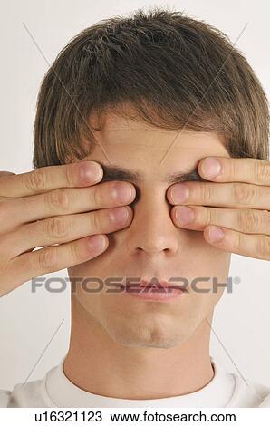 Stock Image - Young male adult; hands covering eyes. Fotosearch