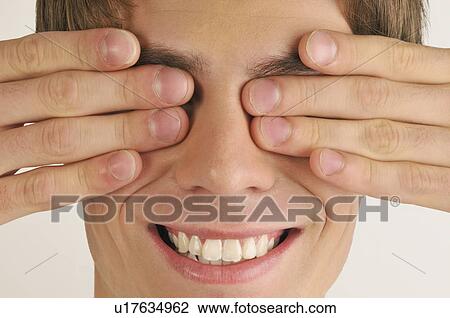Stock Image - Young male adult; hands covering eyes. Fotosearch