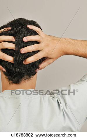 Stock Image - Young male adult; holding head in hands. Fotosearch