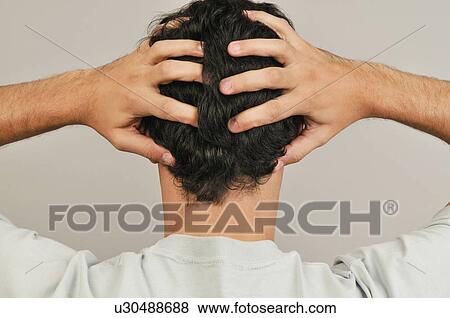 Stock Photo - Young male adult; holding head in hands. Fotosearch