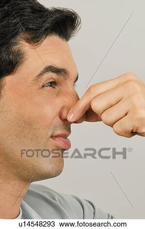 Stock Image - Young male adult holding nose. Fotosearch