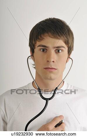 Stock Image - Young male adult; listening to his heart with stethoscope. Fotosearch