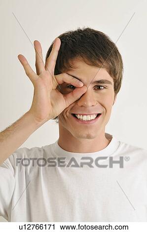 Stock Image - Young male adult; looking through fingers' hole. Fotosearch