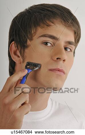 Picture - Young male adult shaving face with razor. Fotosearch
