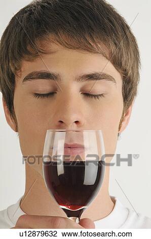 Stock Image - Young male adult smelling a glass of red wine. Fotosearch