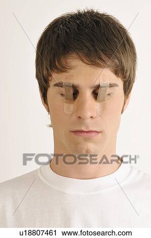 Stock Image - Young male adult with Band-Aids over his eyes. Fotosearch