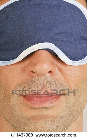 Stock Photo - Young male adult with night shade over eyes. Fotosearch