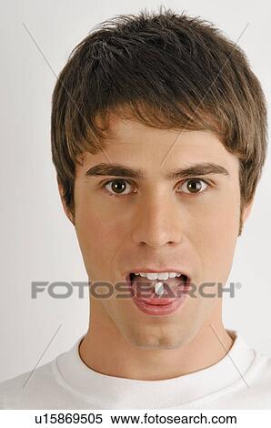 Stock Photography - Young male adult with pill on tongue. Fotosearch