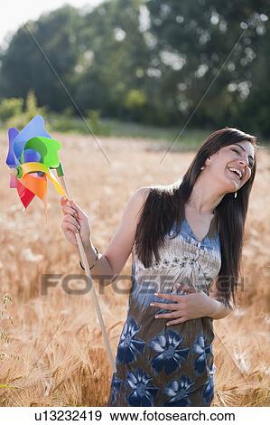 Stock Photo - Young woman holding pinwheel in wheat field. Fotosearch