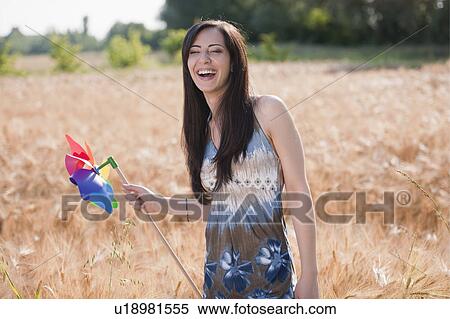 Stock Photography - Young woman holding pinwheel in wheat field. Fotosearch