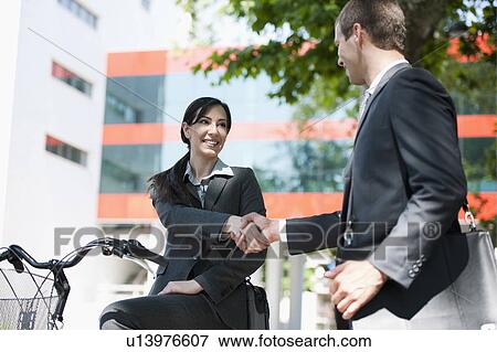 Stock Photo - Young woman on bike shaking hands with businessman . Fotosearch