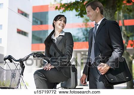 Young woman on bike talking to businessman View Large Photo Image Stock Image - Young woman on bike talking to businessman . Fotosearch