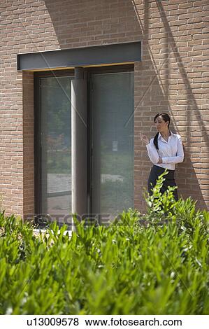 Stock Photo - Young woman smoking a cigarette outside building. Fotosearch