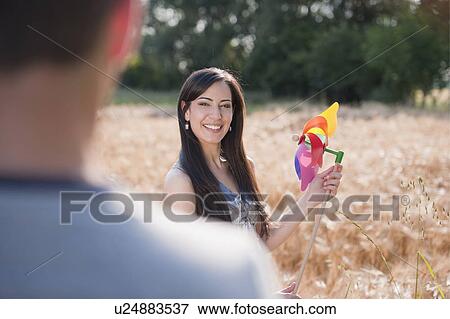 Stock Photo - Young woman with man holding pinwheel in wheat field . Fotosearch