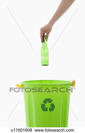 Stock Photo - Young woman's arm throwing glass bottle in the recycling bin. Fotosearch